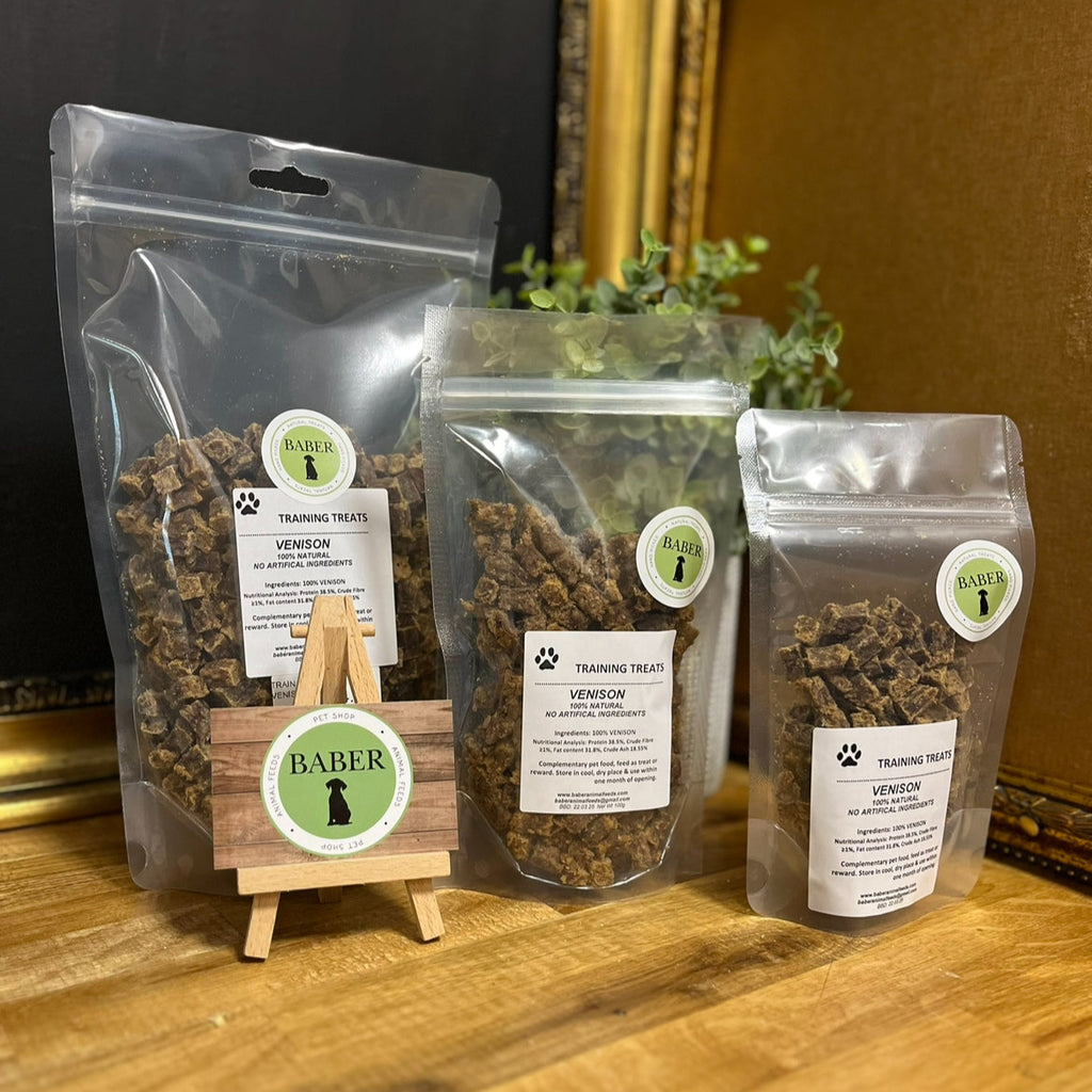 Three packages of dog treats with visible branding on a wooden surface.